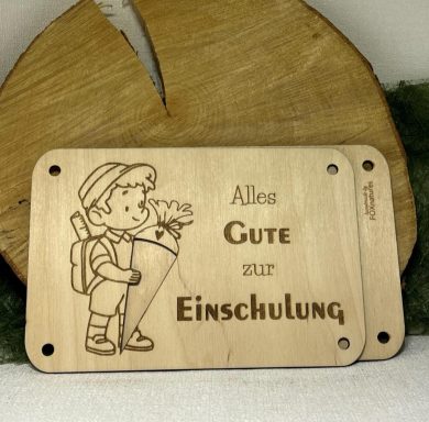 Holschild mit einem Jungen, der eine Schultüte hält, und dem Text "Alles Gute zur Einschulung".